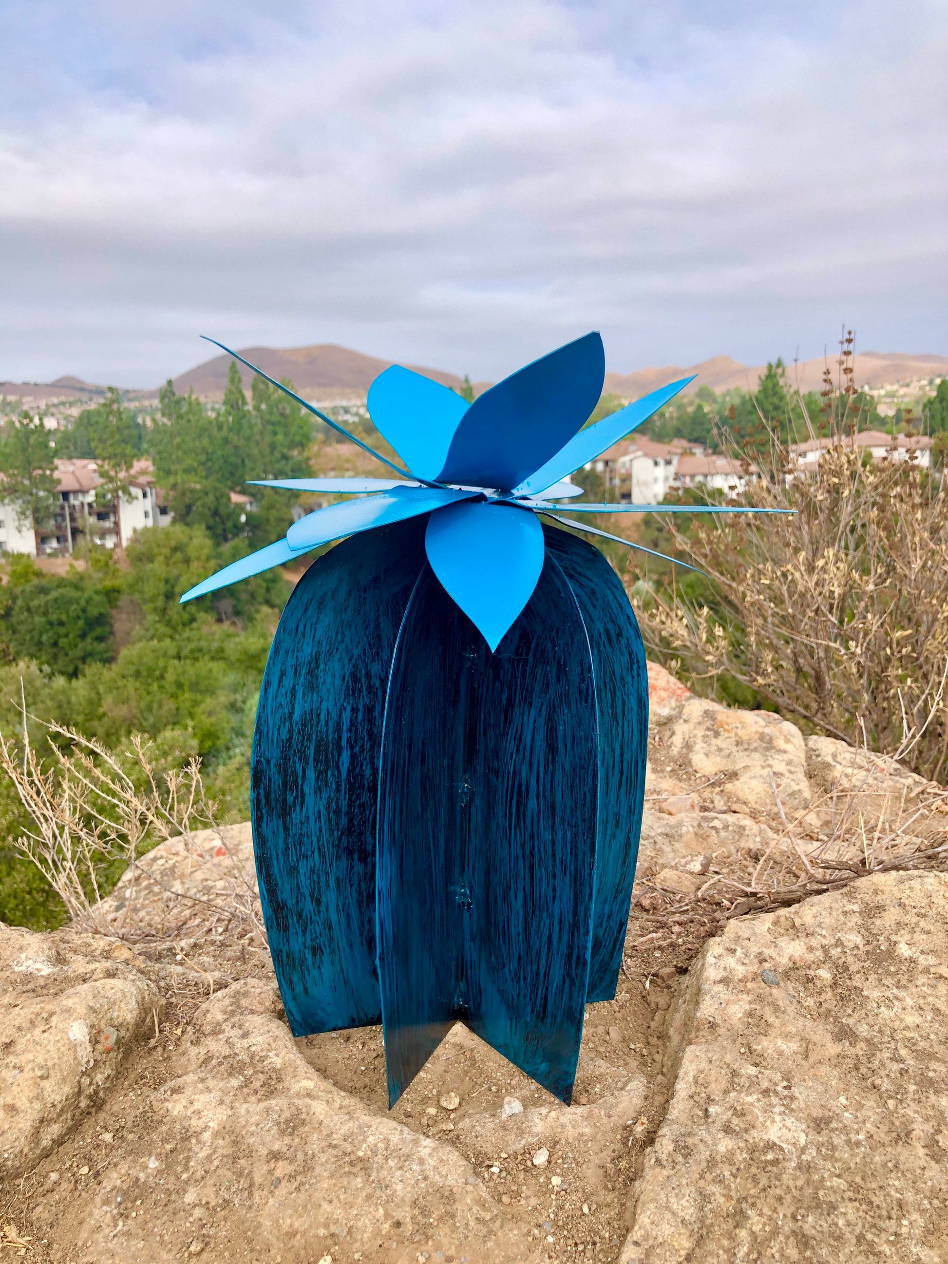 Axel Lily handcrafted steel lily — brushed black stem with lagoon blue flower, patio setting