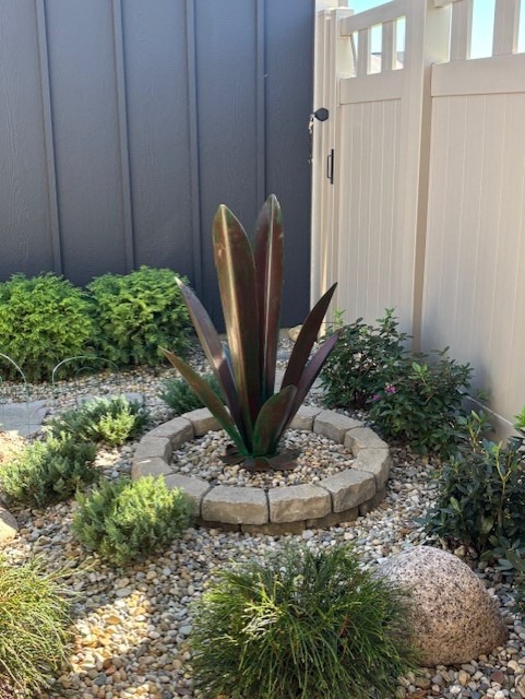 Steel agave in a circular stone border, surrounded by gravel and low courtyard planting
