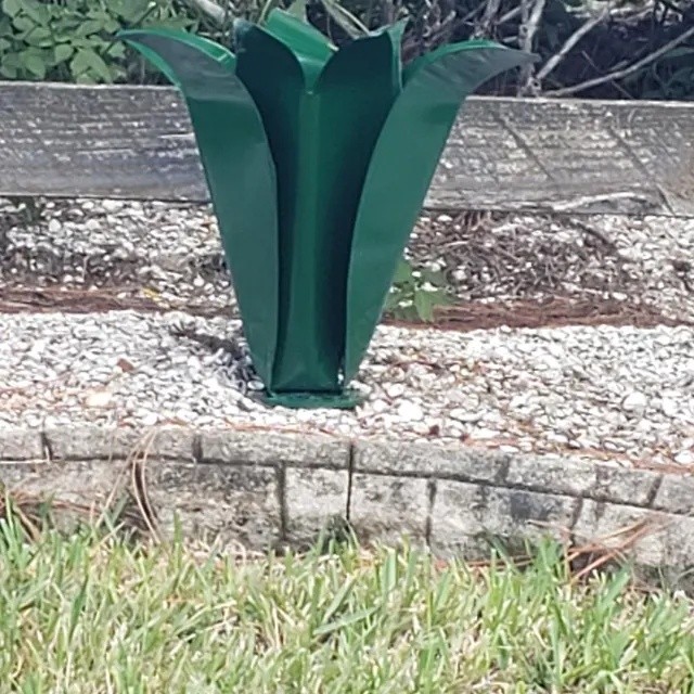 Green steel Blossom installed in a planted garden bed with gravel and a low stone edge