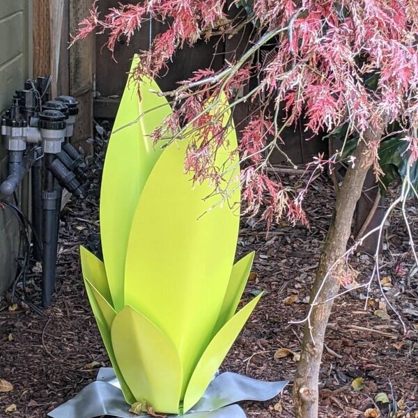 Lime-colored steel sculpture beneath the branches of a Japanese maple