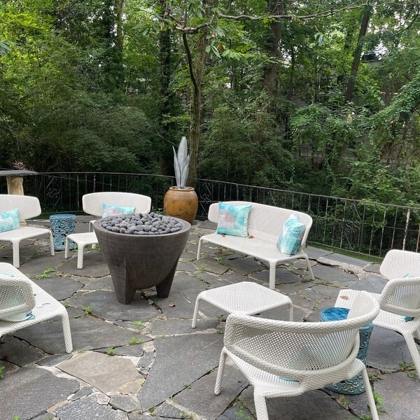 Tall steel flower sculptures in planters beside white patio seating