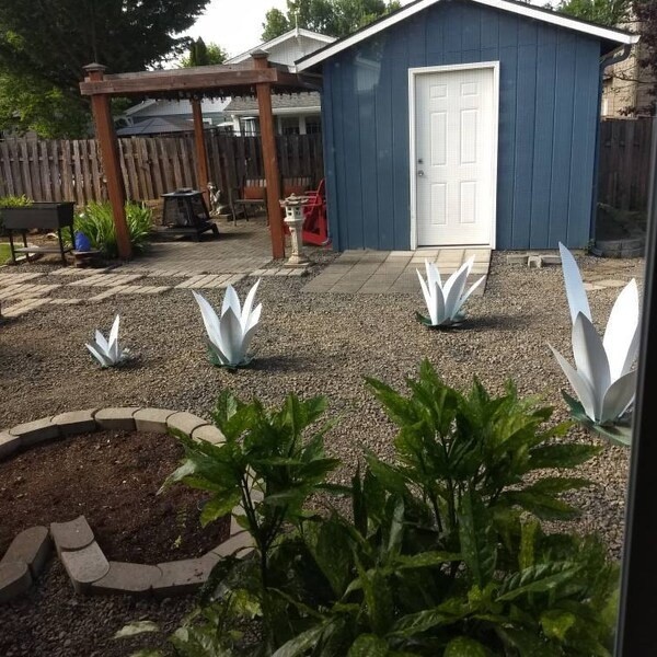 White steel flower sculptures spaced through an open garden bed